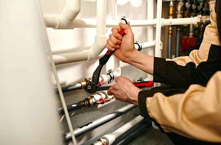 Técnico perito de Adisa Recicla realizando la calibración y el ajuste de válvulas en una red interior de agua caliente sanitaria (ACS).