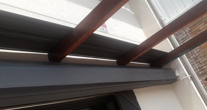 Toldo corredero negro con lona impermeable instalado por Josegra bajo viga protectora.